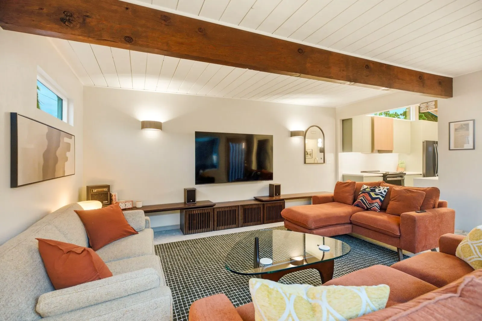 Media lounge with rust-orange sofas under vaulted beams