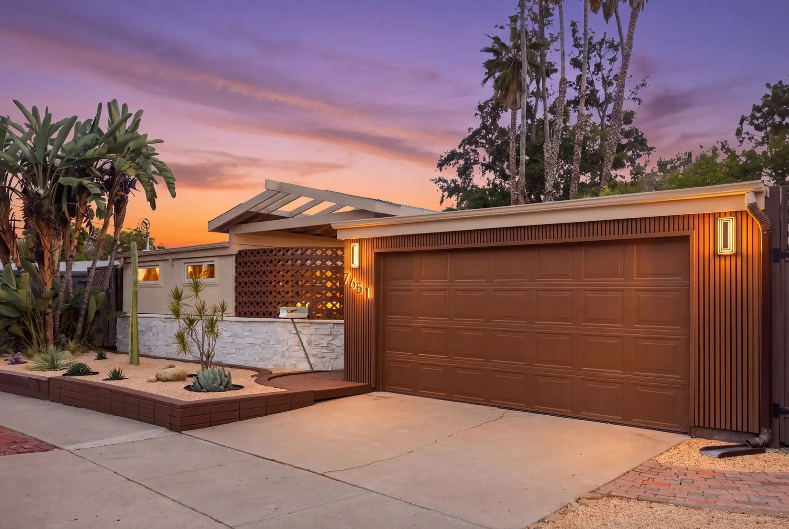The midcentury front of the house at dusk with the garage
